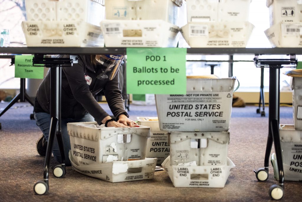 A worker kneels on the floor while looking through a box of absentee ballots Tuesday, Nov. 3, 2020, at Milwaukee’s Central Count facility. Angela Major/WPR