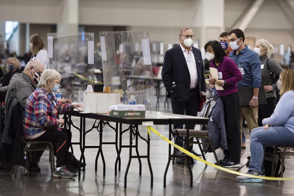 Observers lean forward to watch recount workers Monday, Nov. 23, 2020, at the Wisconsin Center in Milwaukee. Angela Major/WPR