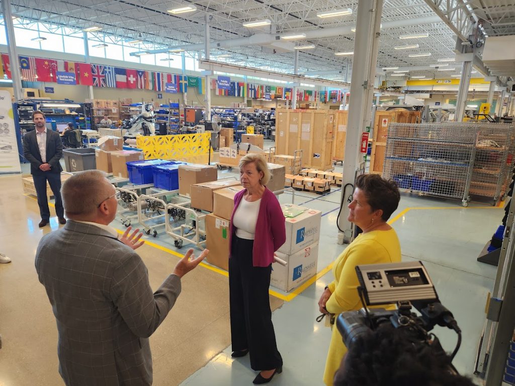 Mike Hoge, senior vice president for global operations at Accuray, takes Sen. Tammy Baldwin (D-Wis.), center, and Wisconsin Economic Development Corp. CEO Missy Hughes, right, on a tour of the company in August. Accuray, part of the Wisconsin biohealth tech hub, makes radiation treatment equipment. (Erik Gunn | Wisconsin Examiner)