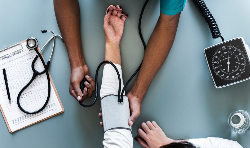 A healthcare professional performing blood pressure monitoring on a patient. (Public Domain).