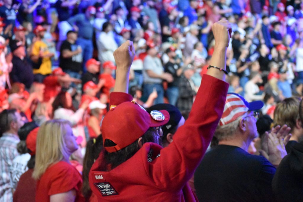 A Trump supporter raises their arms and cheers during a rally in the Resch Center in Ashwaubenon on Oct. 30, 2024. Joe Schulz/WPR