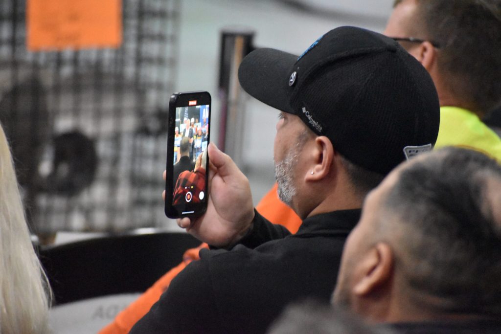 An audience member records Democratic Vice Presidential candidate Tim Walz’s speech in Manitowoc Pattern and Machining in Manitowoc, Wis. on Oct. 28, 2024. Joe Schulz/WPR