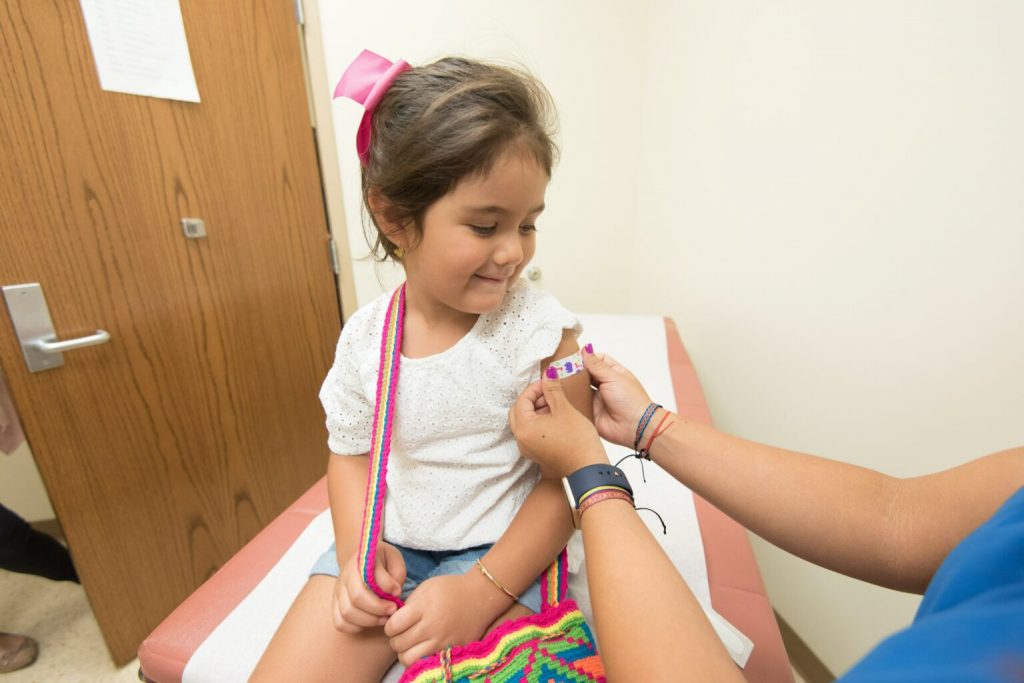 A health care worker places a bandage on a child after giving a vaccination shot. (Scott Housley | CDC)