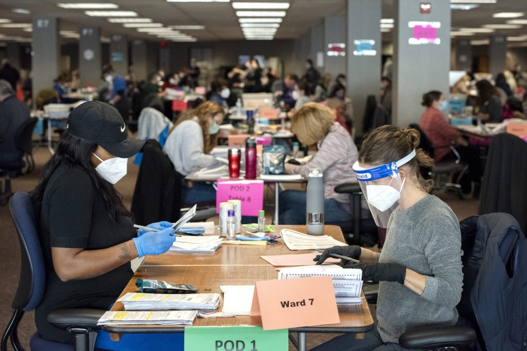 Workers in masks and gloves remove ballots from envelopes Tuesday, Nov. 3, 2020, at Milwaukee’s Central Count facility. Angela Major/WPR