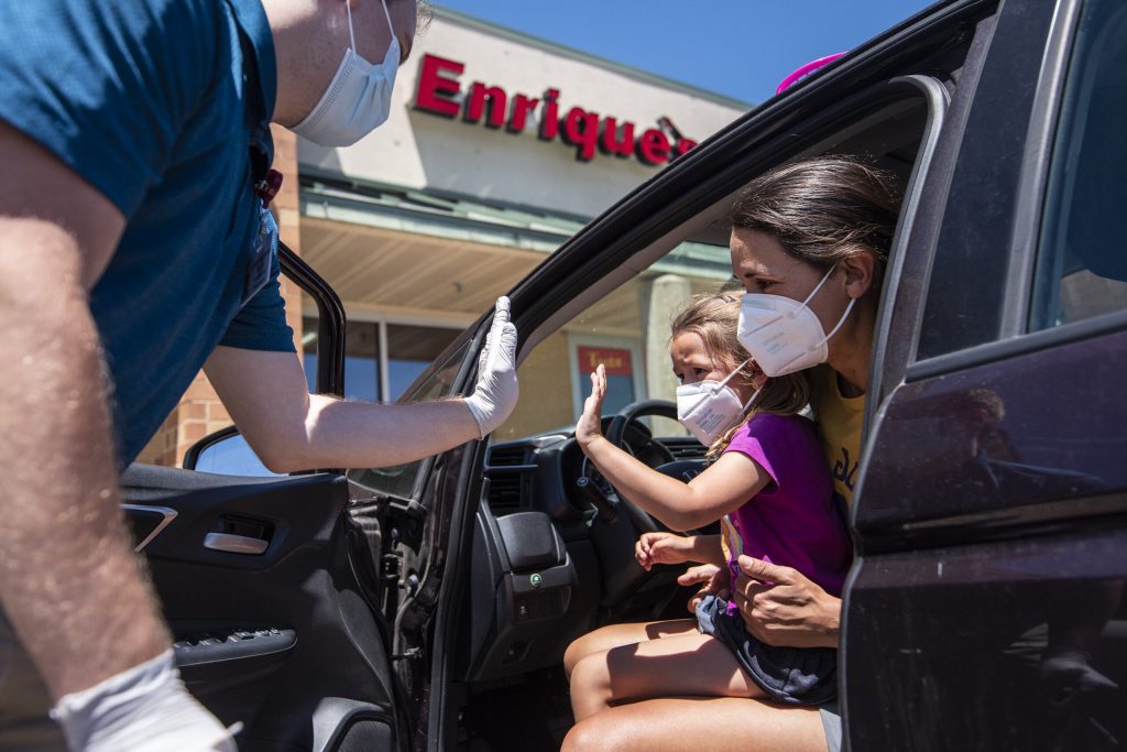 Mary Ann Feutz holds her daughter, Zoe Klabunde, as she gets a high-five after receiving a COVID-19 vaccine Wednesday, June 22, 2022, at Fitchburg Family Pharmacy in Fitchburg, Wis. Angela Major/WPR