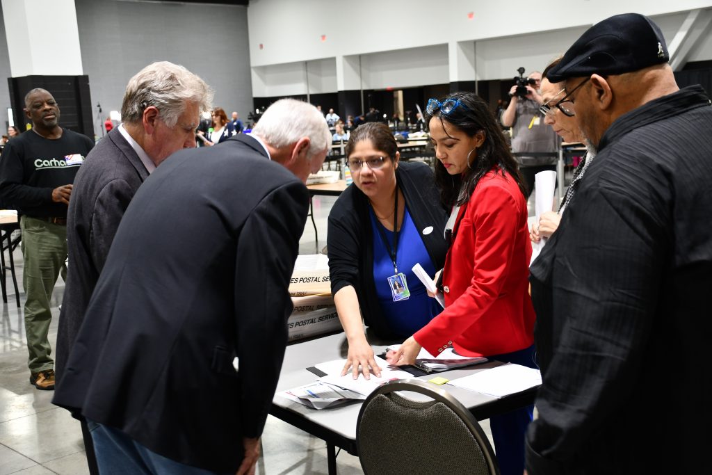 Sen. Ron Johnson (center) inspects a log book while MEC executive director Paulina Gutierrez highlights relevant areas. Photo by Jeramey Jannene.