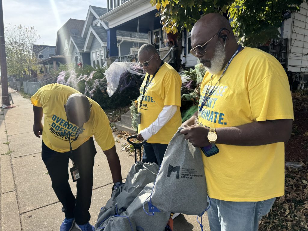 Sean Braxton, Vincent McClellan and Ricky Person with Milwaukee County look through resource bags aimed at reducing the number of overdose deaths in the community. Evan Casey/WPR