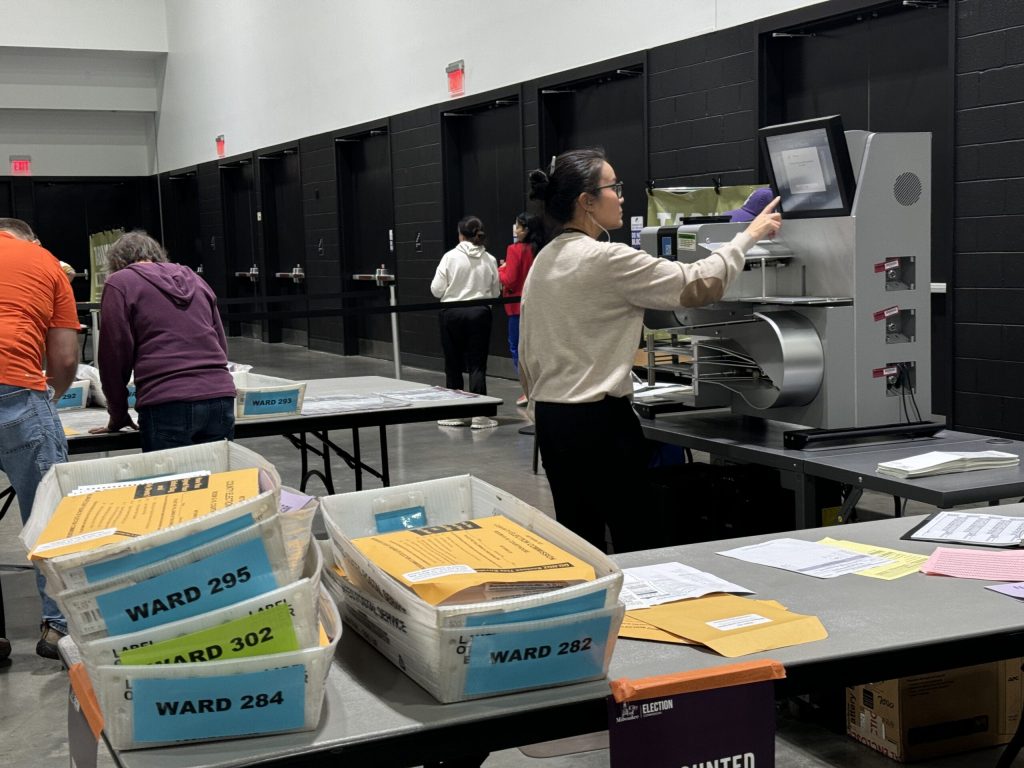 A poll worker at the city of Milwaukee central count facility works on a tabulating machine. Evan Casey/WPR