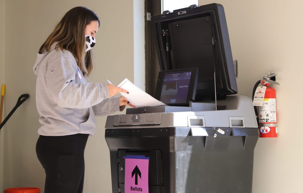 A poll worker inserts absentee ballots into a voting machine at Lakeview Lutheran Church on Madison’s north side on Nov. 3, 2020. Steven Potter/WPR