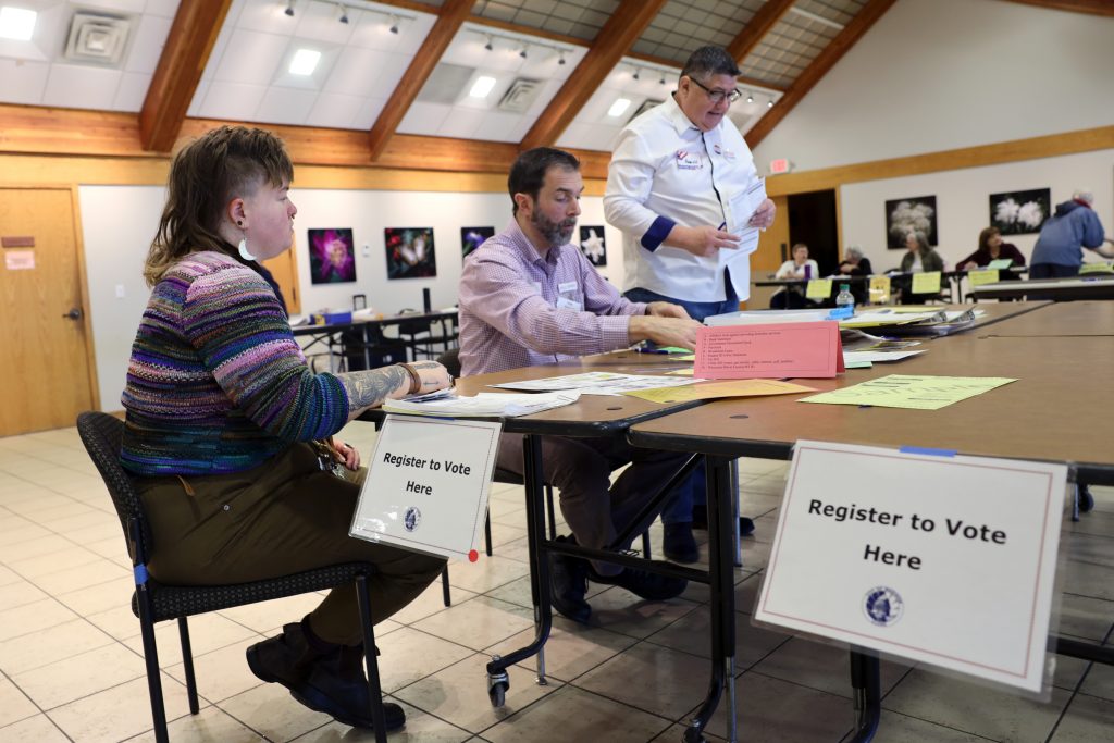 Wisconsin voters on the list for possible deactivation because they have moved can change their addresses at the polls on Election Day. Here, Alix Yarrow, left, registers to vote at the polling place at Olbrich Botanical Gardens in Madison, Wis., on Feb. 18, 2020. Yarrow had recently changed addresses within the city. Assisting in the registration process are Kyle Richmond, center, and Aaron Schultz, right. Coburn Dukehart/Wisconsin Watch