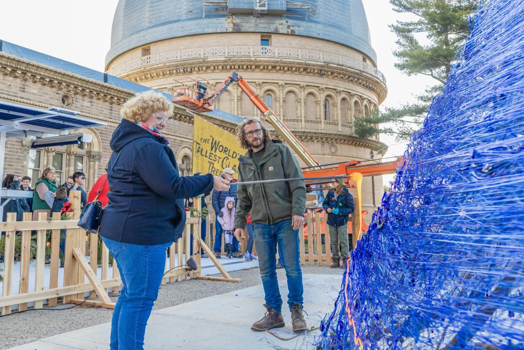 Photo credit: World's Tallest Glass Tree, artist Jason Mack oversees attendees putting on liquid glass