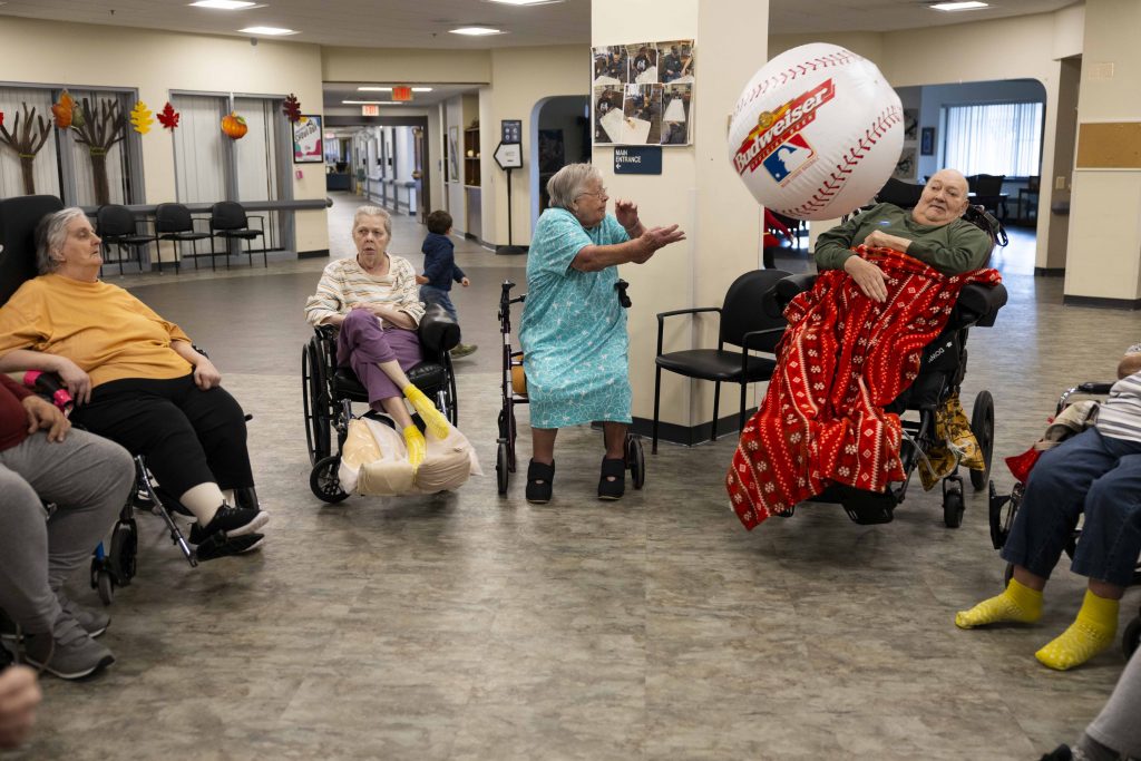 Arlene Meyer throws an inflatable baseball to another resident during her morning ball exercises on Nov. 15, 2024, at Pine Crest Nursing Home in Merrill, Wis. Meyer has lived in the nursing home since late 2023. (Joe Timmerman / Wisconsin Watch)