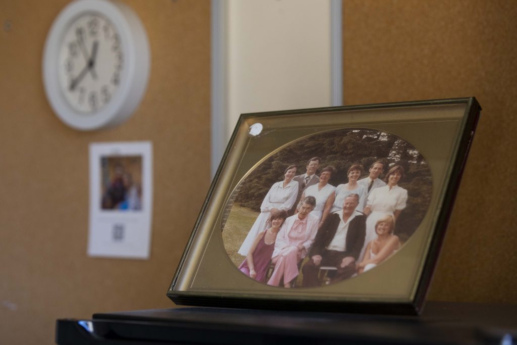 A family picture is framed on top of Arlene Meyer’s refrigerator in her room at Pine Crest Nursing Home in Merrill, Wis., on Nov. 15, 2024. Meyer is third from the left in the top row of the picture. (Joe Timmerman / Wisconsin Watch)