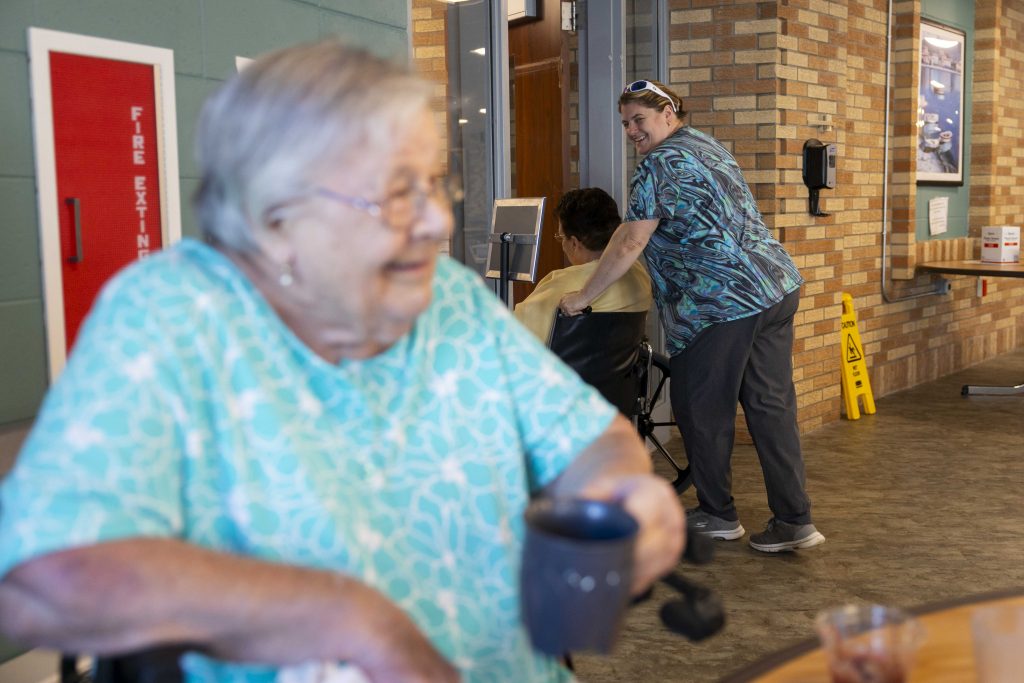 Arlene Meyer laughs with Paula Streich, a certified nursing assistant, right, while eating lunch with three of her fellow Pine Crest Nursing Home residents in Merrill, Wis., on Nov. 15, 2024. (Joe Timmerman / Wisconsin Watch)