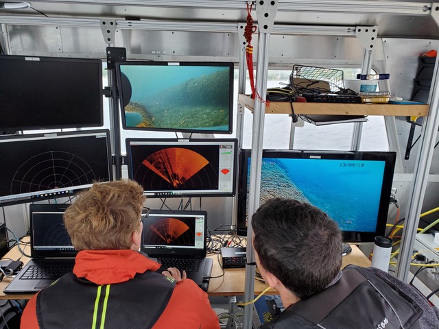 Two researchers look at screens during an underwater scanning mission. Photo courtesy of Ed Bailey with Northwestern Michigan College