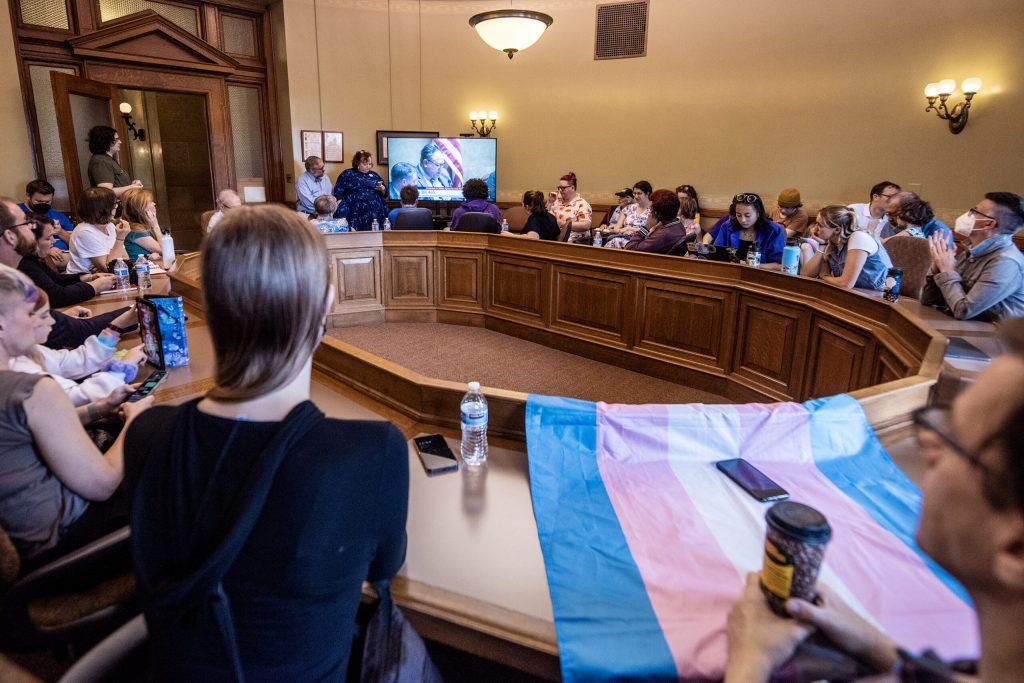 A striped transgender pride flag is on display as people watch a public hearing on Assembly Bill 465 from an overflow room Oct. 4, 2023, at the Wisconsin State Capitol in Madison, Wis. The bill would ban providing certain types of gender-affirming medical care to minors. Angela Major/WPR