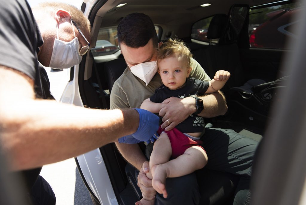 Ted Lenoch holds his 15-month-old son, Remy, a he receives a COVID-19 vaccine Wednesday, June 22, 2022, at Fitchburg Family Pharmacy in Fitchburg, Wis. Angela Major/WPR