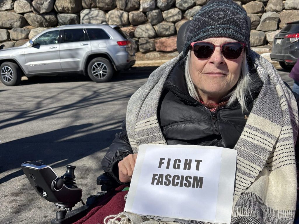 Barbara Vedder holds a sign that says, “Fight Fascism” at a demonstration outside of Sen. Ron Johnson’s office on Feb. 25, 2025. Addie Costello/WPR