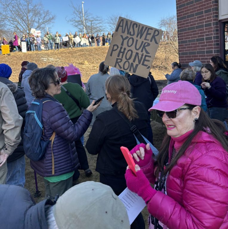 A Madison protestor holds up a cardboard sign that says, “Answer your phone, Ron.” Addie Costello/WPR