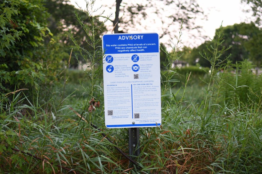 A sign warning of PFAS risks in Starkweather Creek in Madison, Wis., is posted along the creek at McCormick Park on July 20, 2021. PFAS are a sometimes toxic family of more than 12,000 compounds commonly found in consumer products like food wrappers, nonstick pans and raincoats along with firefighting foam used to smother hot blazes. (Isaac Wasserman / Wisconsin Watch)