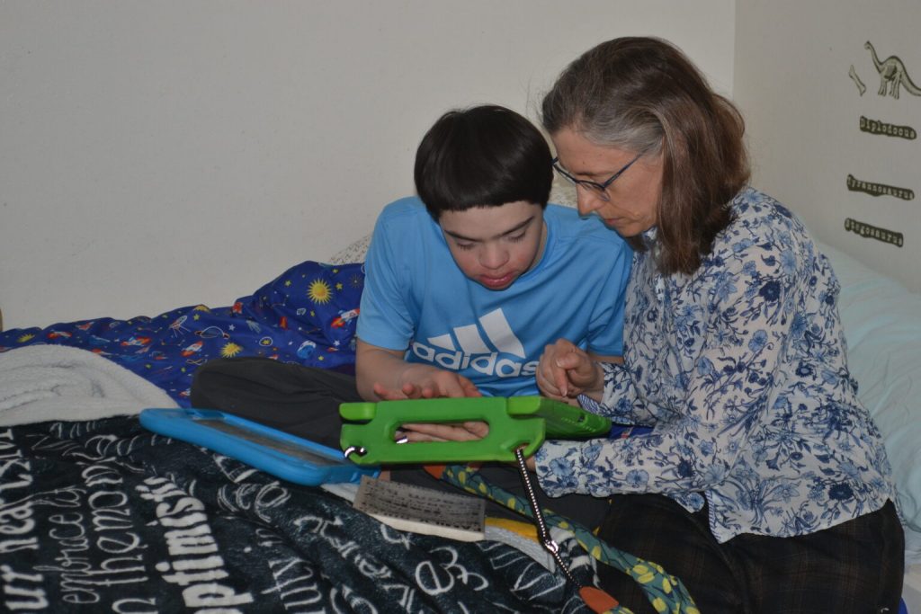 Max Glass-Lee uses an electronic communication device, picking words that the device then speaks to his mother, Tiffany Glass. (Photo by Erik Gunn/Wisconsin Examiner)