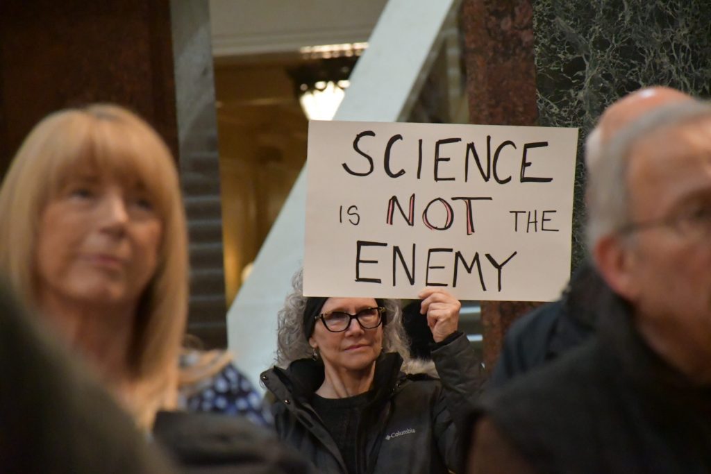 A protester holds a sign that reads “Science Is Not The Enemy,” at the “Stand Up For Science” rally in Madison. Mackenzie Krumme/WPR