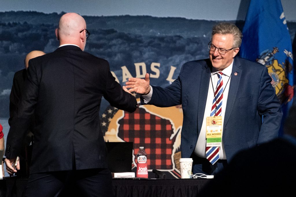 Republican Party of Wisconsin Chair Brian Schimming, right, shakes hands with US Rep. Derrick Van Orden, left, as he takes the stage Saturday, May 17, 2025, during the Republican Party of Wisconsin State Convention in Rothschild, Wis. Angela Major/WPR