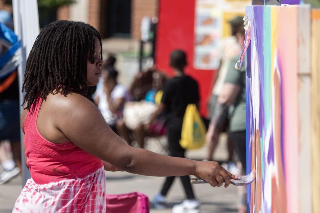 Artist Anna Rose Menako paints a mural during the Juneteenth Jubilee Parade on Thursday, June 19, 2025, in Milwaukee, Wis. An artist statement explaining the theme of her piece stated, “My idea of freedom prioritizes the right to creative expression, the right to daydream, and the right to desire without pressure or trauma.” Angela Major/WPR