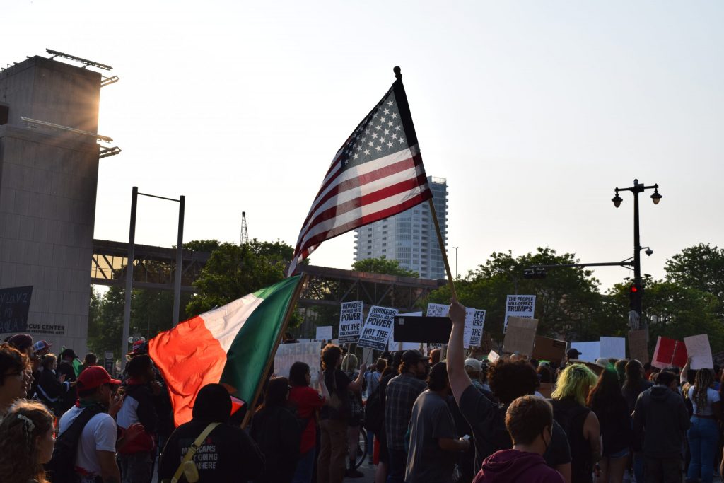 Protesters wave a Mexican flag and American flag outside of the Milwaukee office for the U.S. Department of Homeland Security on June 10, 2025, during a protest against the Trump administration’s and law enforcement’s recent immigration raids. Evan Casey/WPR