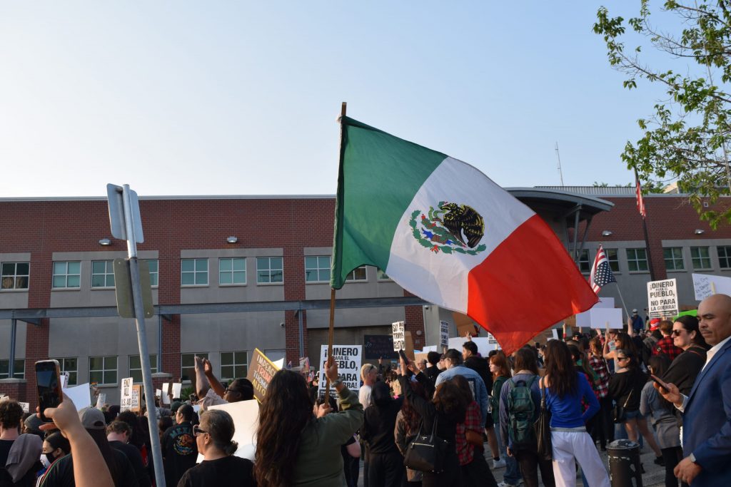 A protester waves a Mexican flag outside of the Milwaukee office for the U.S. Department of Homeland Security. Evan Casey/WPR