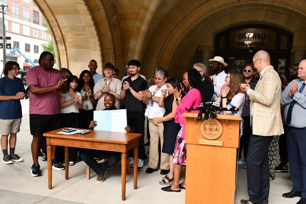 Mayor Cavalier Johnson presents signed Housing Element plan, while Diana Vang-Brostoff wipes back tear. Photo by Jeramey Jannene.