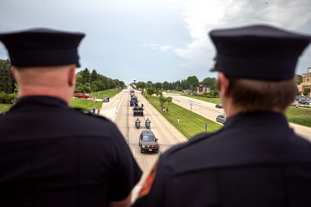 Brookfield firefighters watch as a funeral procession for Milwaukee Police Officer Kendall Corder drives by Friday, July 11, 2025, in Brookfield, Wis. Angela Major/WPR