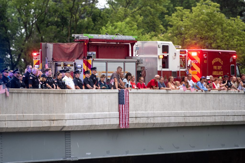 People watch as a funeral procession for Milwaukee Police Officer Kendall Corder passes by Friday, July 11, 2025, in Brookfield, Wis. Angela Major/WPR