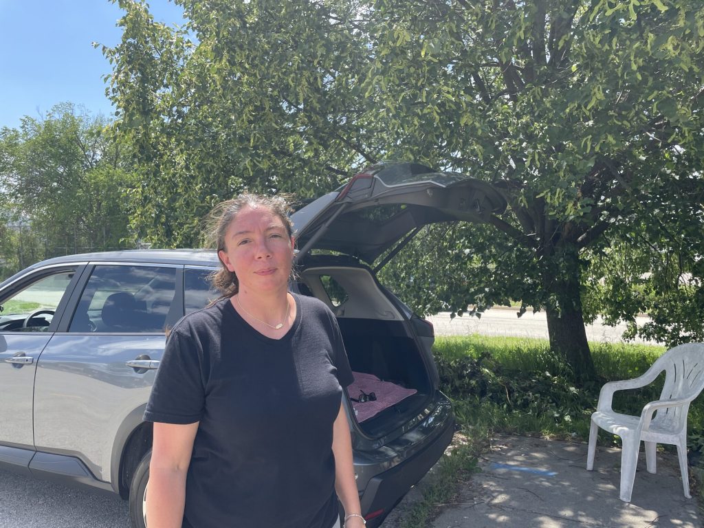 Uber and Lyft driver Vanessa Gasper stands in front of her car at Milwaukee Mitchell International Airport’s rideshare staging lot on June 27, 2025. Nick Rommel/WPR