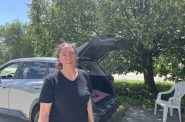 Uber and Lyft driver Vanessa Gasper stands in front of her car at Milwaukee Mitchell International Airport’s rideshare staging lot on June 27, 2025. Nick Rommel/WPR
