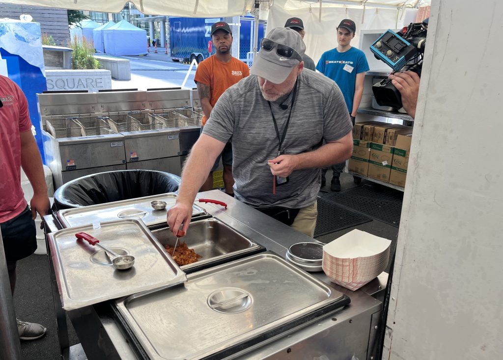 Mike Starks checks the temperature of a pan of chicken at Saz's booth. Photo taken July 18, 2025 by Sophie Bolich.