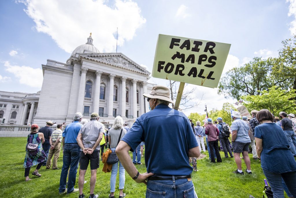 Attendees hold signs at the Rally for Fair Maps on Monday, May 17, 2021, in Madison, Wis. Angela Major/WPR