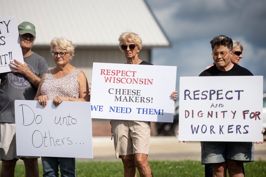 Attendees hold signs in support of striking workers Tuesday, Aug. 19, 2025, at W&W Dairy in Monroe, Wis. Angela Major/WPR