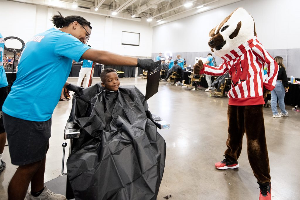 Jalen Johnson with Lifestyle Haircare holds up a mirror for a student to see his haircut Sunday, Aug. 24, 2025, during the JP Hair Design’s Back 2 School Free Haircutz event at the Alliant Energy Center in Madison, Wis. Angela Major/WPR