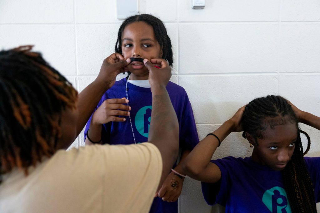 Deloise L. sticks a fake mustache on her son, Dariaz, as her daughter, Da’Netta, fixes her hair during Camp Reunite at Taycheedah Correctional Institution. (Joe Timmerman / Wisconsin Watch)