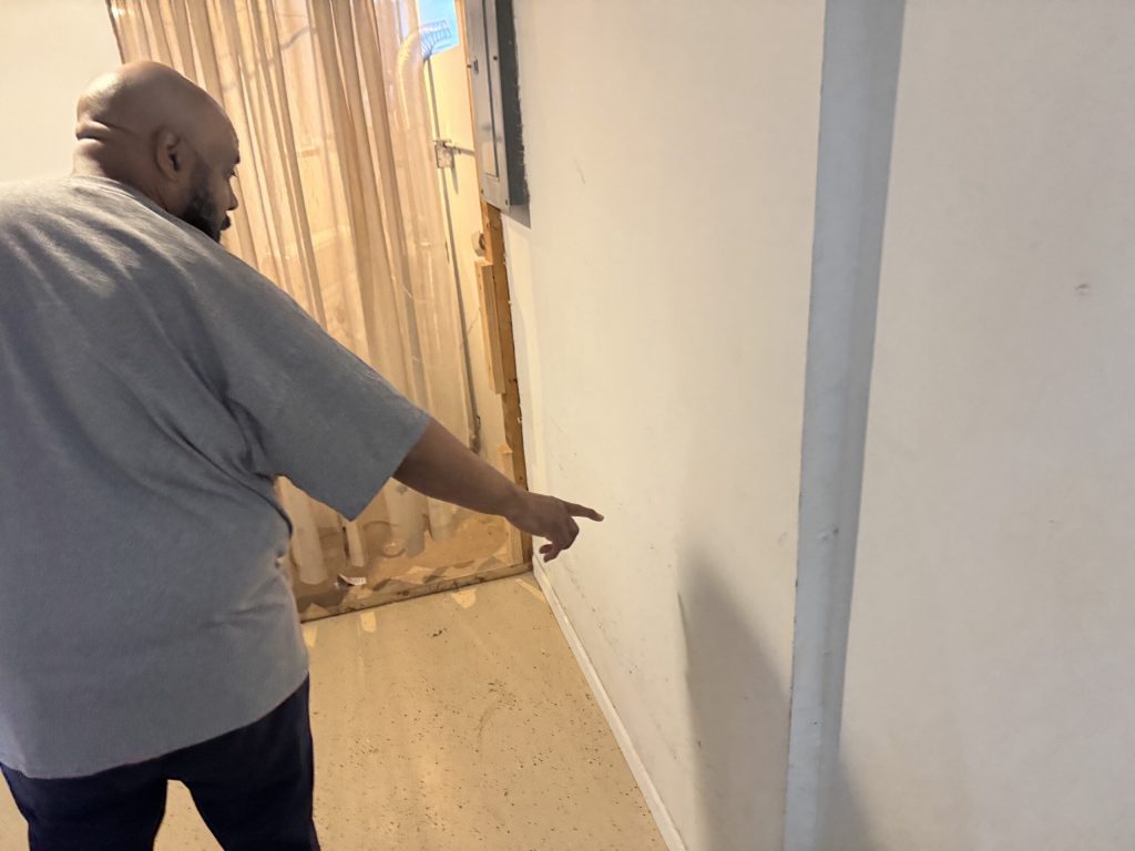 On Aug. 15, 2025, Dwayne Morgan, a resident of Milwaukee’s north side, shows how high the flood water was at in his basement. Evan Casey/WPR