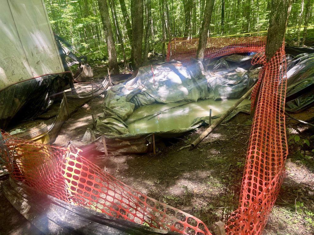 A pit covered by a plastic liner contains drilling, water fluids and cuttings from Green Light Wisconsin’s exploration of the Bend deposit in the Chequamegon-Nicolet National Forest on July 17, 2025. Danielle Kaeding/WPR