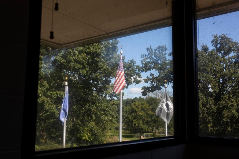 A state of Wisconsin flag, United States of America flag, and a POW/MIA flag fly outside Klein Hall on Monday, Aug. 25, 2025, in Chippewa Falls, Wis. (Joe Timmerman / Wisconsin Watch)