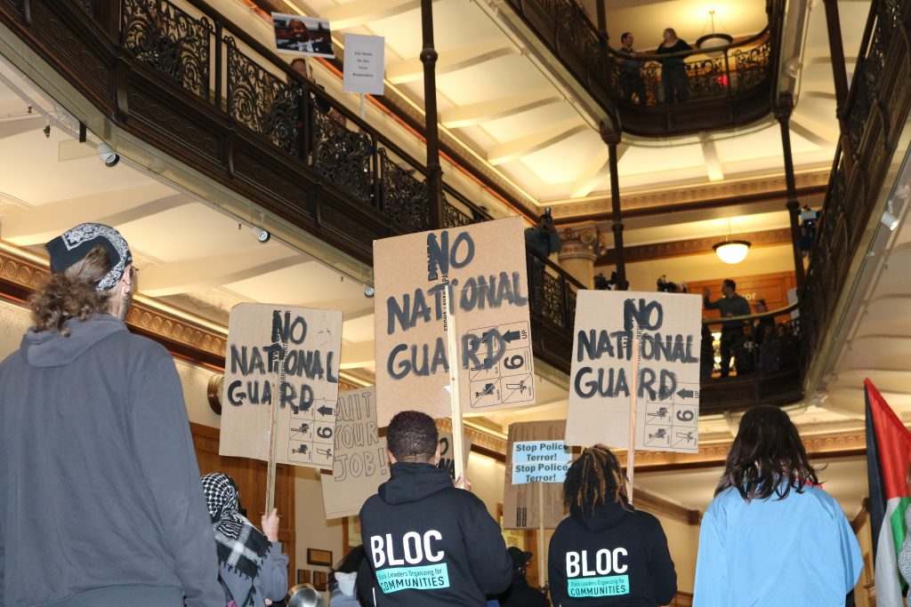 MPA protesters march on the Milwaukee City Hall's second level while counter-protesters assemble in the atrium. Photo by Sophie Bolich.
