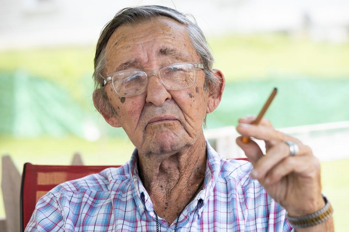 Jimmy Novy smokes a Wrangler cigar on his porch July 29, 2025, in Hillsboro, Wis. (Joe Timmerman / Wisconsin Watch)