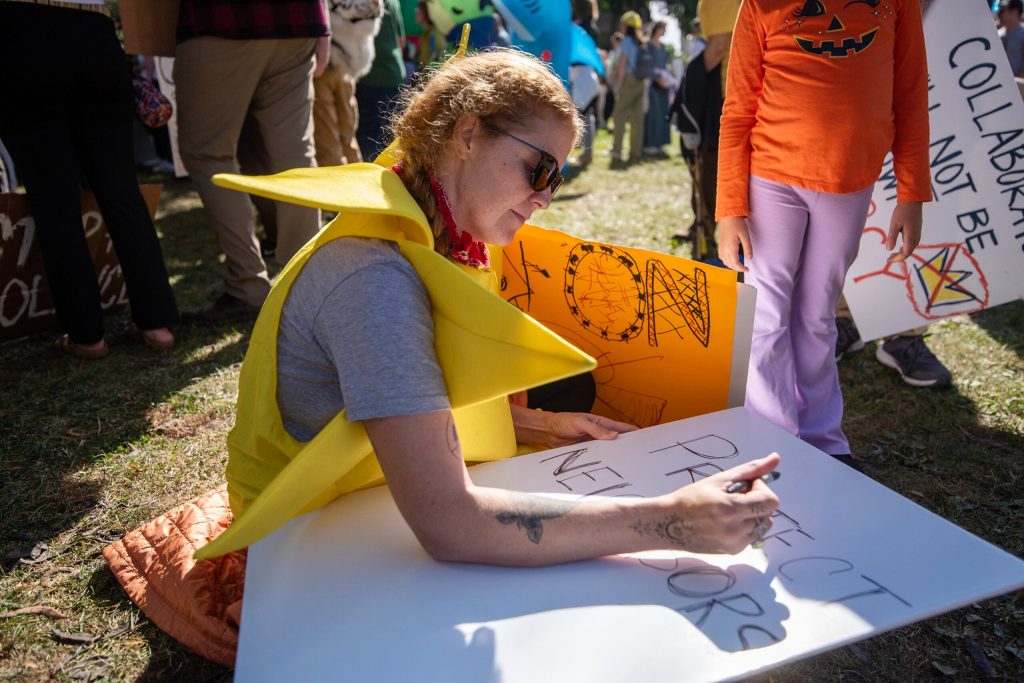 A protester makes a sign during an anti-Trump protest Saturday, Oct. 18, 2025, at Cathedral Square Park in Milwaukee, Wis. Angela Major/WPR