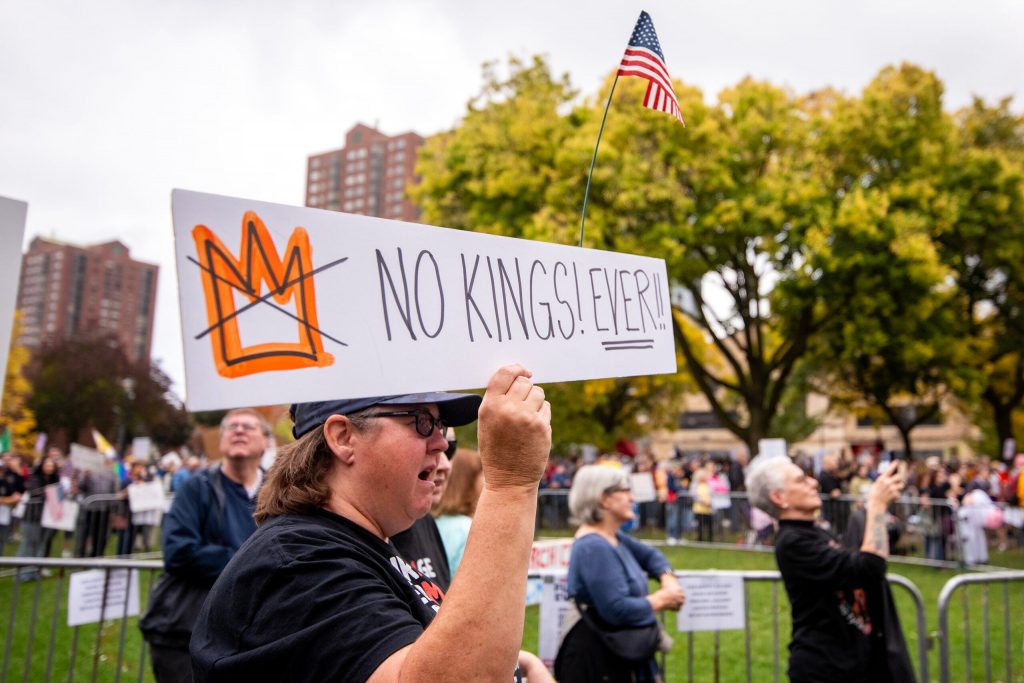 A protester chants and holds a sign before an anti-Trump march Saturday, Oct. 18, 2025, at Cathedral Square Park in Milwaukee, Wis. Angela Major/WPR