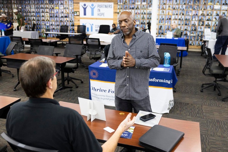 Darnell Price, right, pitches his memoir during a Home to Stay resource fair for people reentering society after incarceration, Oct. 1, 2025, at Community Warehouse in Milwaukee. (Joe Timmerman / Wisconsin Watch)