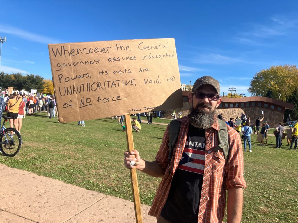 Joe Myatt of Janesville holds a sign reading, “Whensoever the general government assumes undelegated powers, its acts are unauthoritative, voice and of no force,” from Thomas Jefferson’s 1798 Kentucky Resolutions. Sarah Lehr/WPR