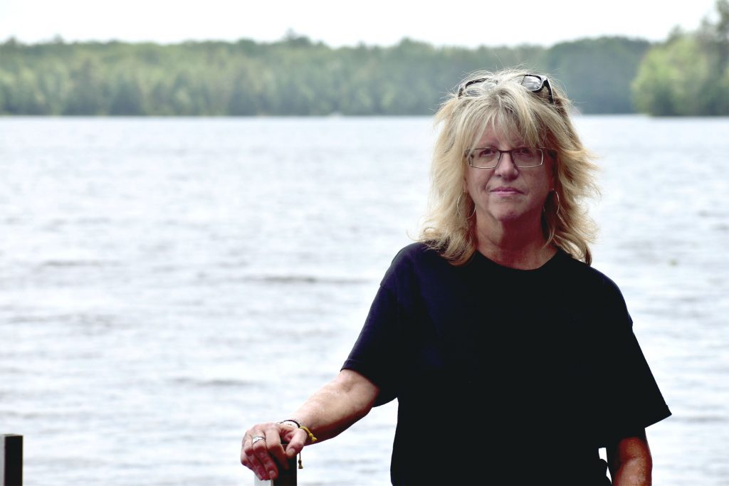 Nancy Sattler, former president of the Moen Lake Chain Association, said she and her neighbors were worried when they first learned of high PFAS levels in the lakes. Sattler is seen here at the Moen Lake boat landing on June 21, 2025. Danielle Kaeding/WPR